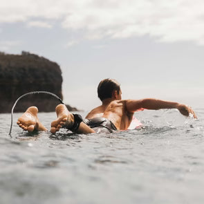 Surfer paddling out wearing FCS x Sharkbanz POD and Sharkbanz wrist bands shark deterrent device